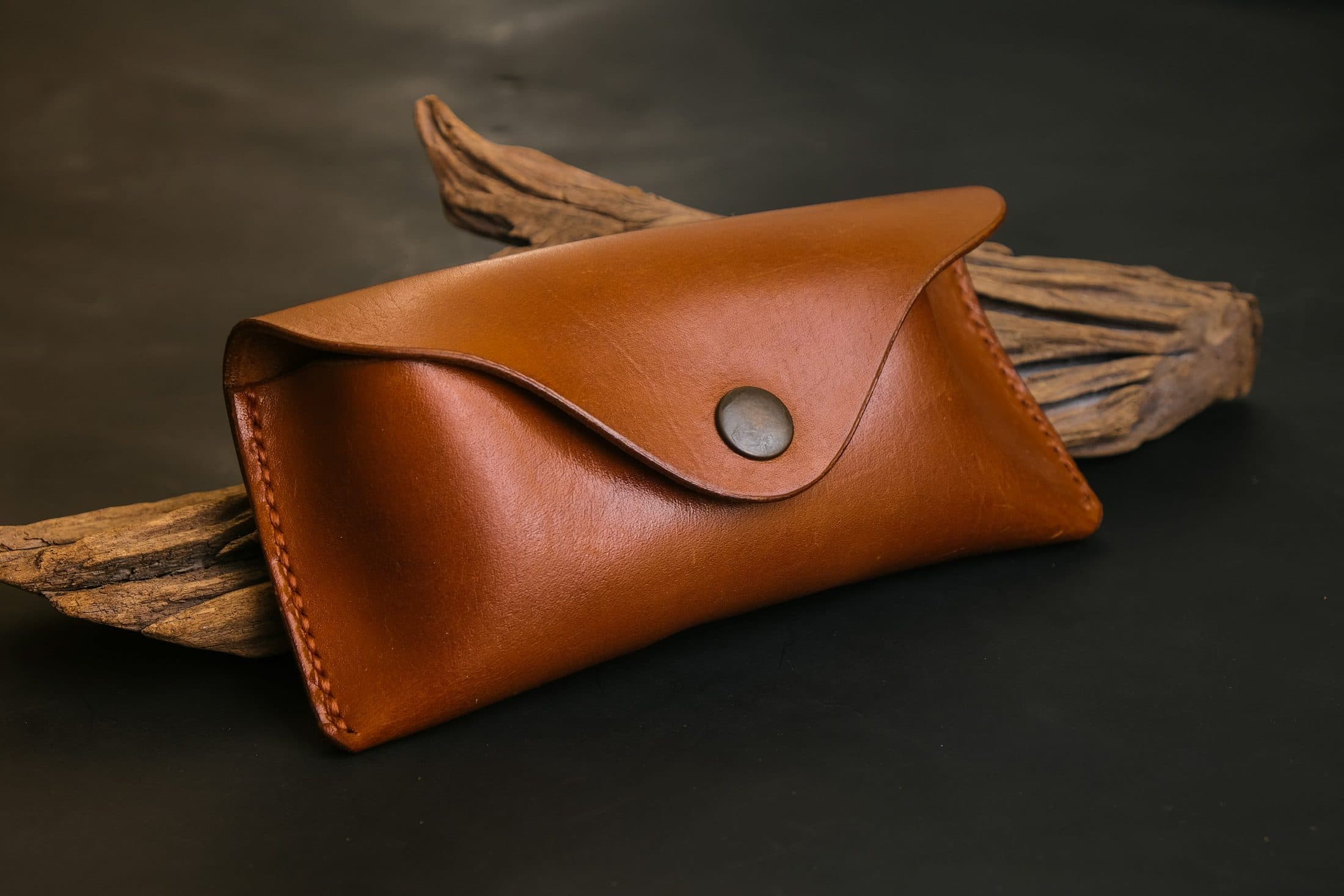 Étui à lunettes en cuir fauve fermé par un bouton-pression