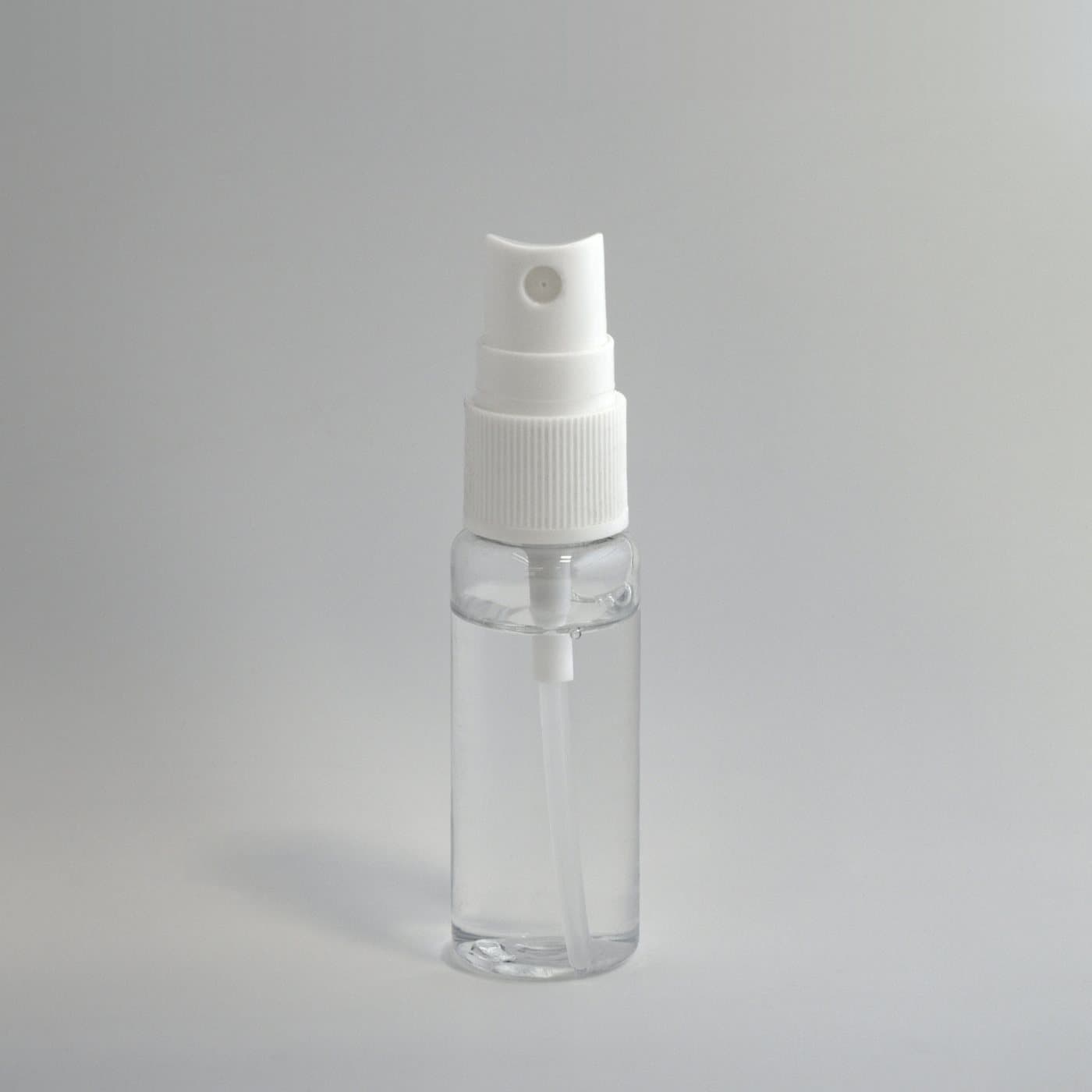 Flacon spray transparent à pompe blanche, sur fond gris clair
